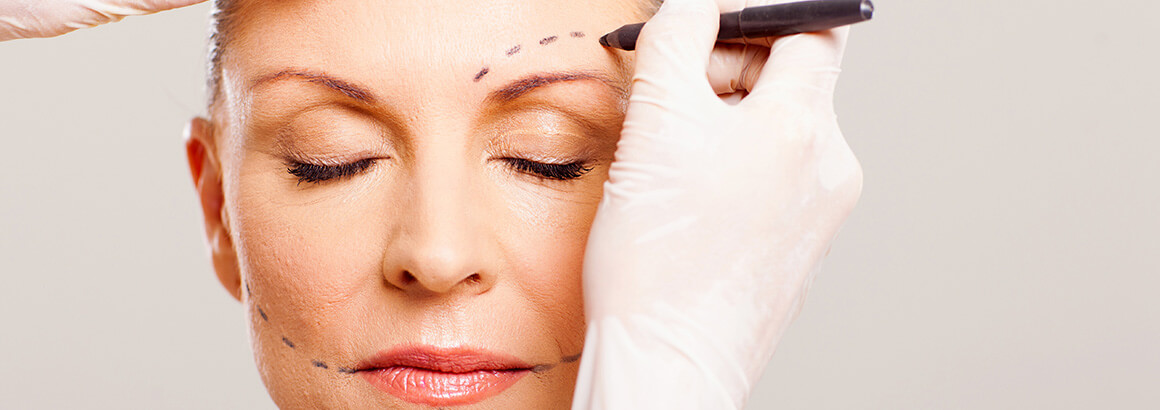 surgeon marking face of senior woman
