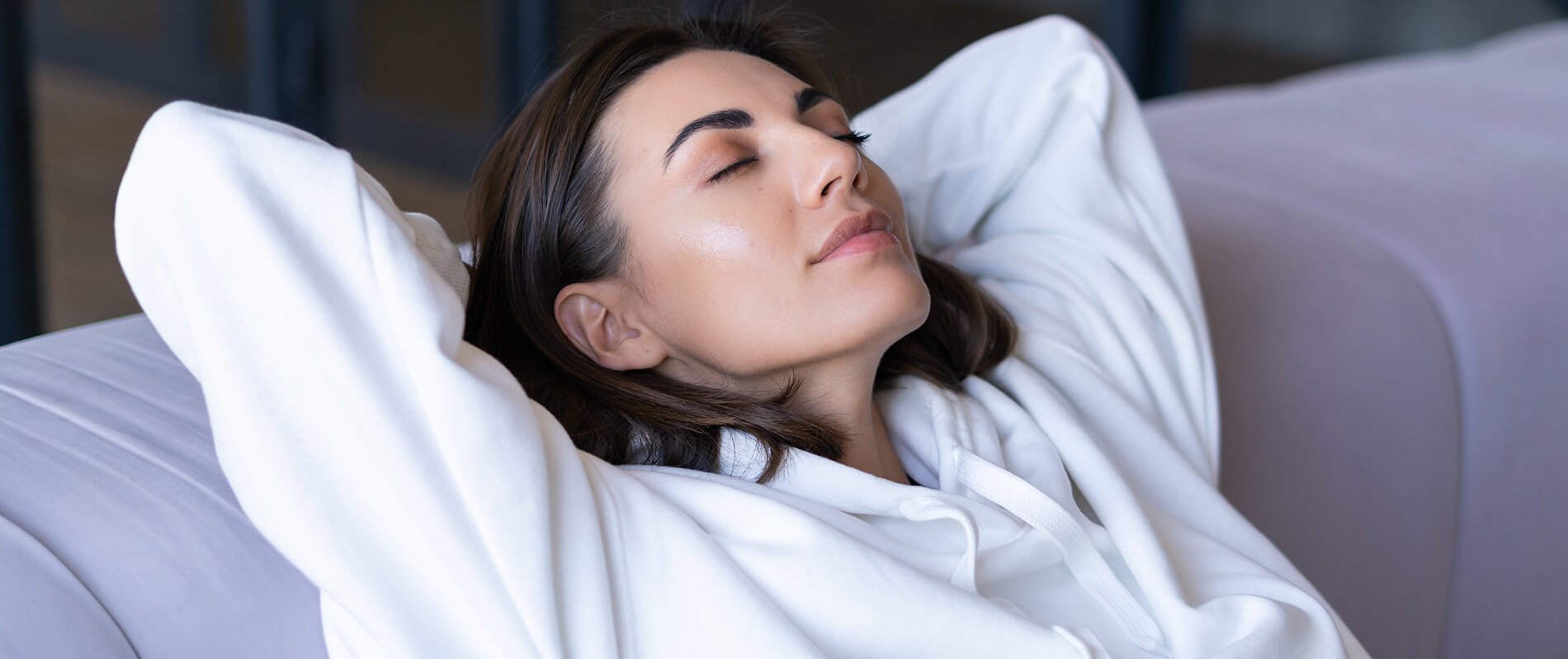 young-woman-home-white-hoodie-couch-serenely-sits-with-closed-eyes